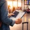 A U.S. traveler holding a passport and travel documents while waiting at an airport, representing travel preparation and travel insurance awareness.