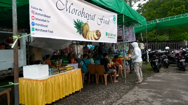 Suasana warung kuliner Morobayat Food di area outdoor dengan pengunjung yang sedang menikmati makanan di bawah tenda hijau